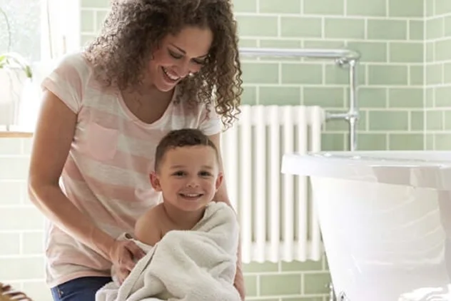 Smiling mother drying her young child with a towel in a bright bathroom